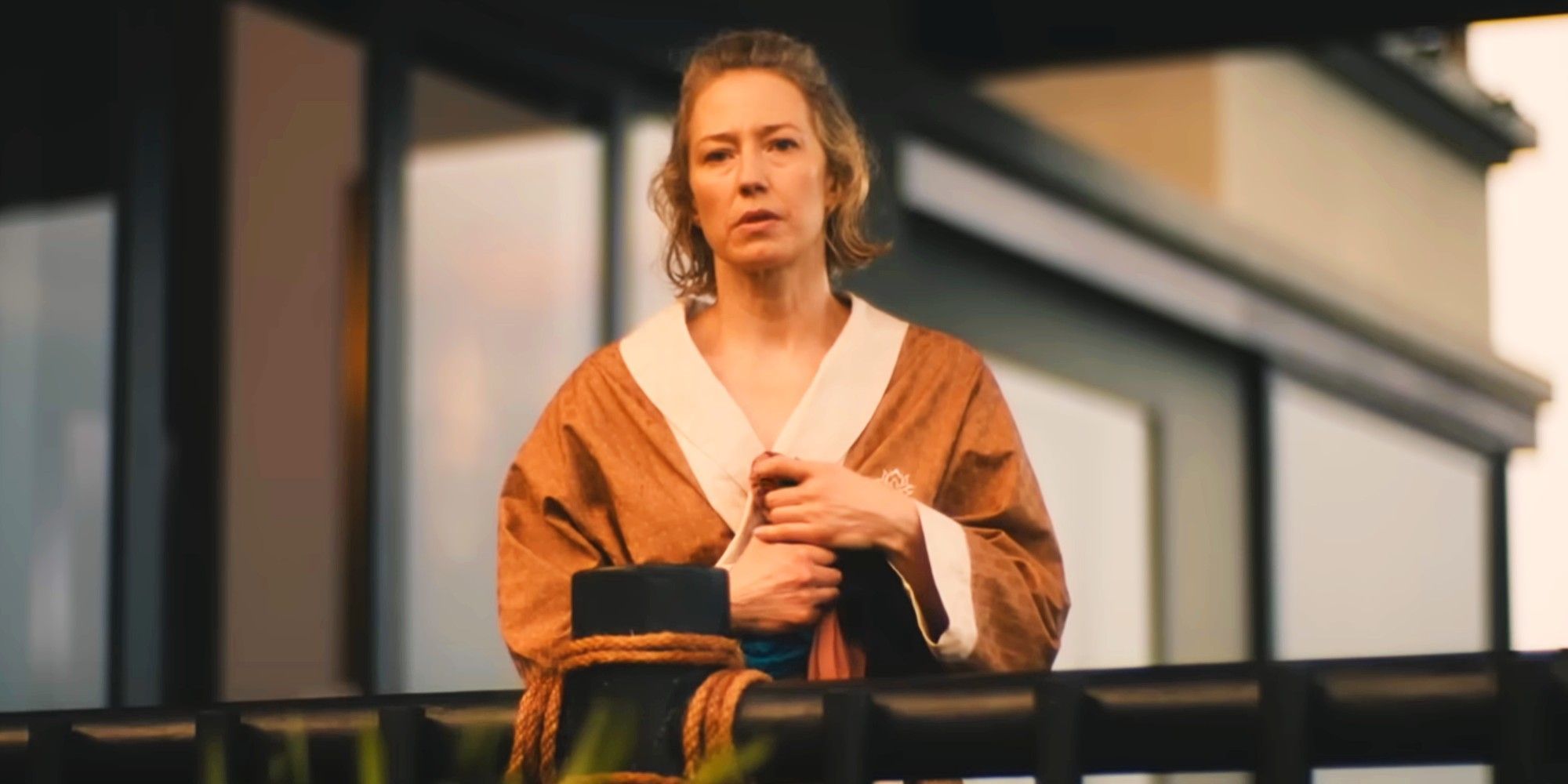 Carrie Coon comme Laurie portant une robe et regardant un balcon dans la saison 3 de la saison 3 de White Lotus 8