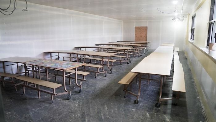 Les tables de cafétéria sont alignées dans une pièce restreinte.