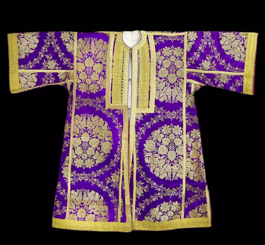 Vêtements traditionnels richement décorés de motifs floraux dorés sur fond violet. Vêtements traditionnels richement décorés de motifs floraux dorés sur fond violet.