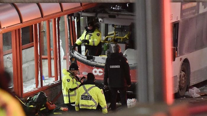 La police en vêtements d'hiver devant un bus accidentel.