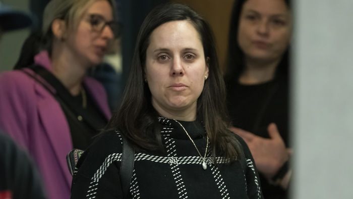 Marie-christine Cloutier regarde l'objectif dans un couloir du palais de justice de Laval, entouré d'autres femmes.