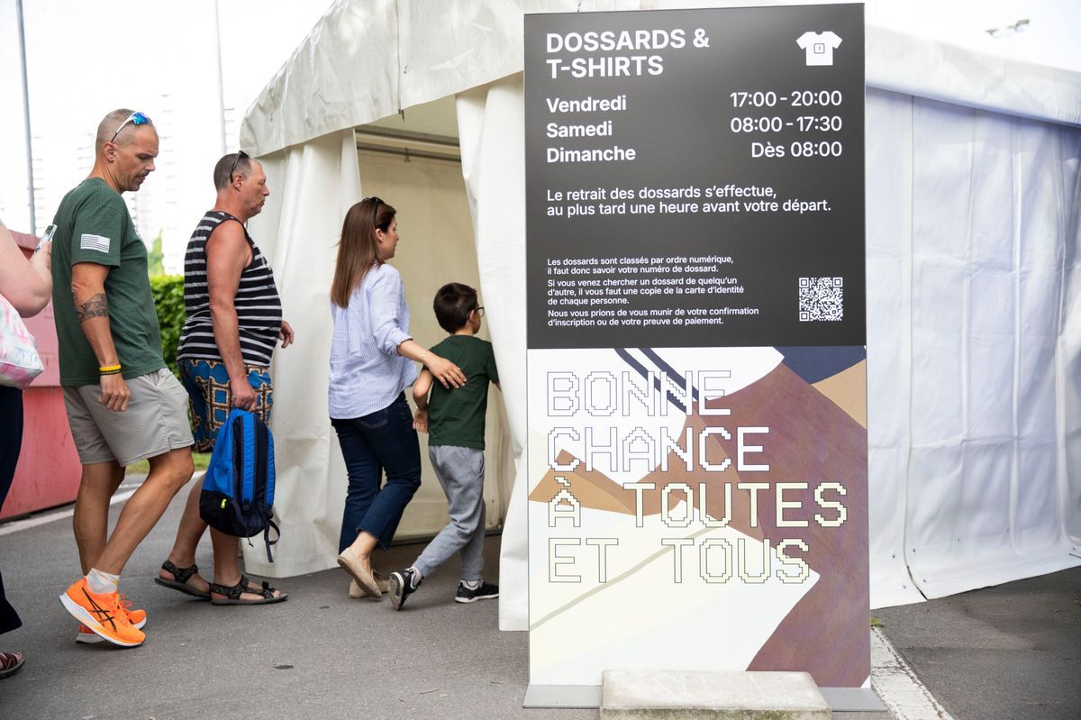 Participants à la file d'attente pour récupérer les bavoirs et les t-shirts pour les 20 km de Lausanne, le 2 mai 2025. Panel indiquant les horaires et souhaitant bonne chance. Participants à la file d'attente pour récupérer les bavoirs et les t-shirts pour les 20 km de Lausanne, le 2 mai 2025. Panel indiquant les horaires et souhaitant bonne chance.
