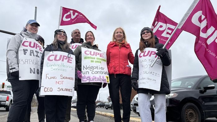 Six employés en grève des services d'audience canadiens à Sudbury et le député de France Gélinas se tenant devant la caméra.