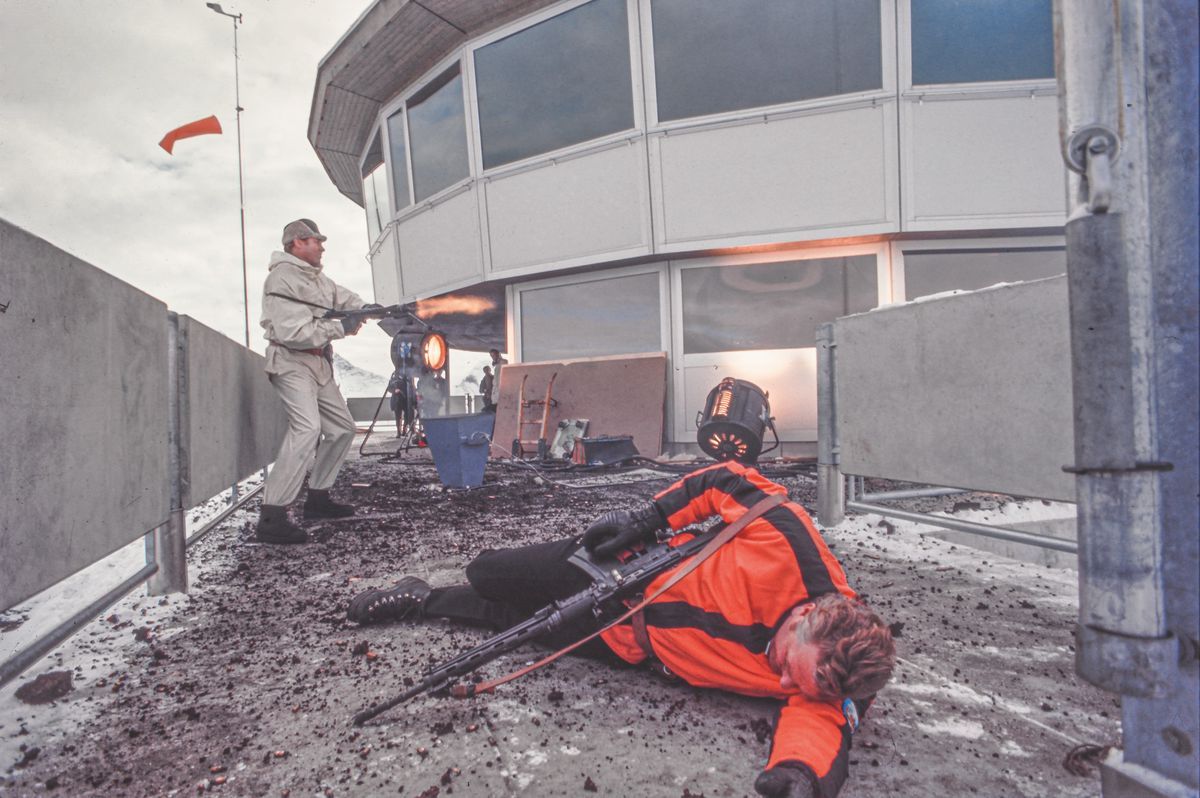 Scène du film montrant une confrontation explosive à Piz Gloria, avec un personnage blanc tirant sur l'ennemi sur le sol. Scène du film montrant une confrontation explosive à Piz Gloria, avec un personnage blanc tirant sur l'ennemi sur le sol.