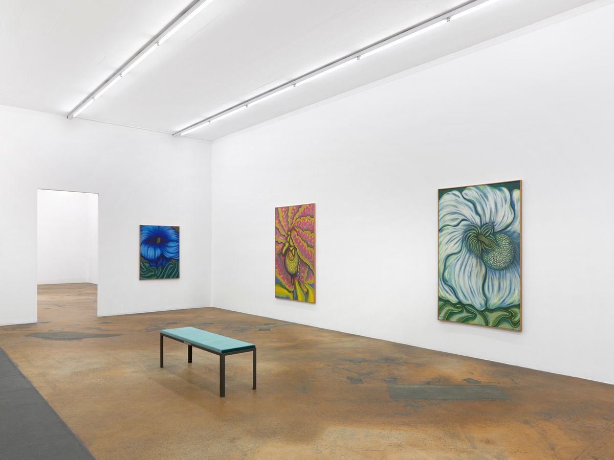 Galerie d'art contemporaine avec des peintures florales colorées accrochées aux murs blancs et à un banc au centre. Galerie d'art contemporaine avec des peintures florales colorées accrochées aux murs blancs et à un banc au centre.