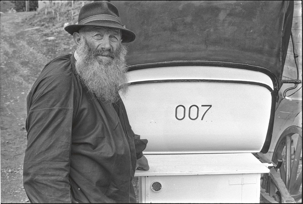 Un homme barbu portant un chapeau à côté d'une voiture avec le numéro 007 sur le siège arrière. Un homme barbu portant un chapeau à côté d'une voiture avec le numéro 007 sur le siège arrière.