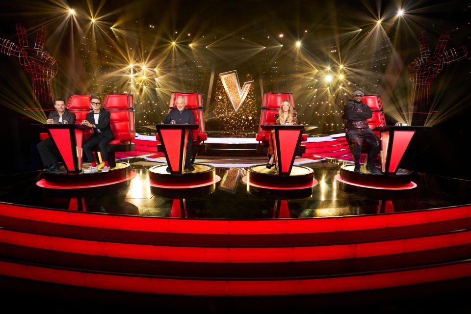 Les juges de la voix britannique, Sir Tom Jones, Leann Rimes, Danny Jones et Tom Fletcher, et Will.i.am, assis dans leurs chaises rouges sur scène.