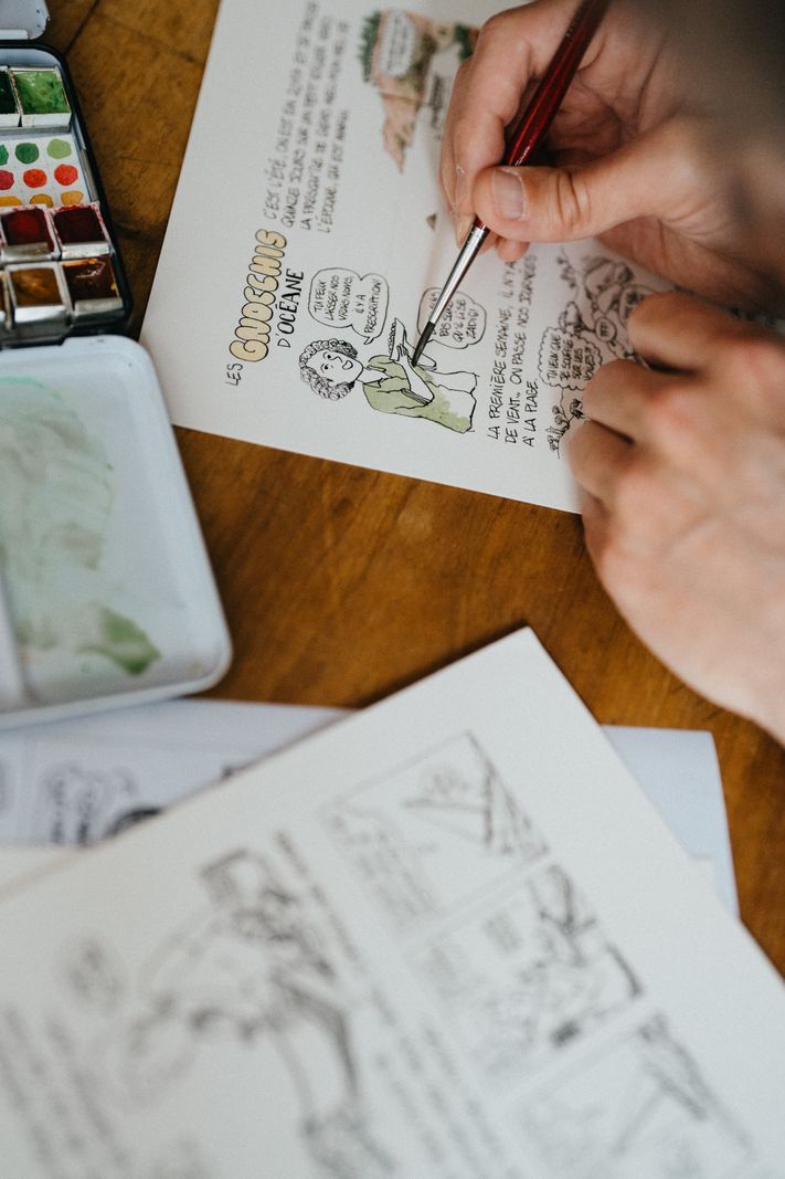 Personne ne dessinait des croquis sur du papier avec une brosse, entouré de palettes de couleurs. Personne ne dessinait des croquis sur du papier avec une brosse, entouré de palettes de couleurs.