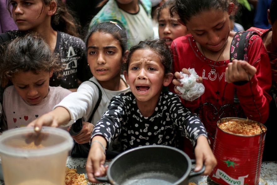 Les enfants palestiniens attendent de recevoir un repas chaud dans un organisme de bienfaisance à Gaza-Ville, le 30 avril 2025