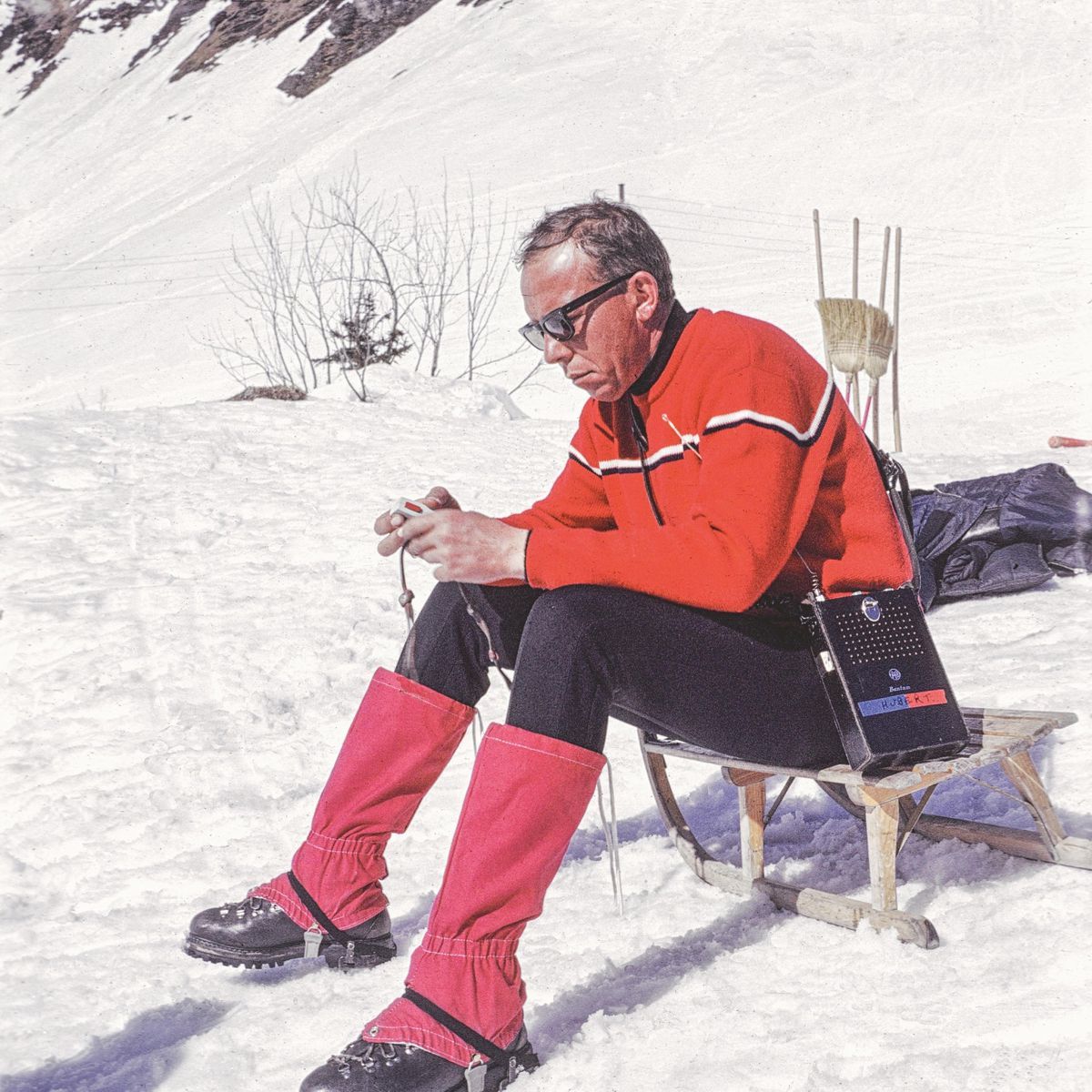 Hubert Fröhlich en pause sur la neige, vêtu d'une tenue rouge, avec des montagnes en arrière-plan. Hubert Fröhlich en pause sur la neige, vêtu d'une tenue rouge, avec des montagnes en arrière-plan.
