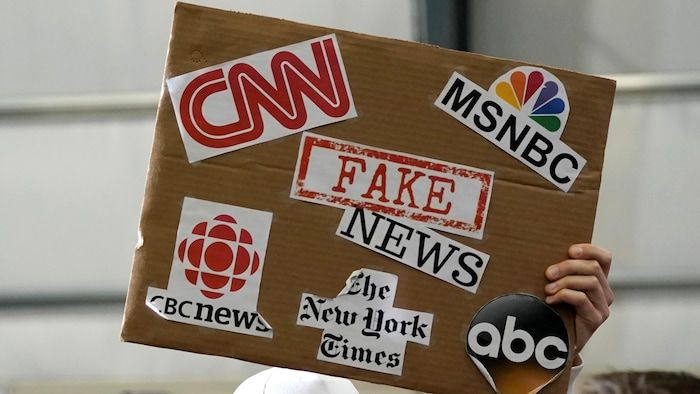 Un partisan du président Donald Trump a brandi un panneau associant de fausses nouvelles à des médias tels que CNN, CBC News et le New York Times.